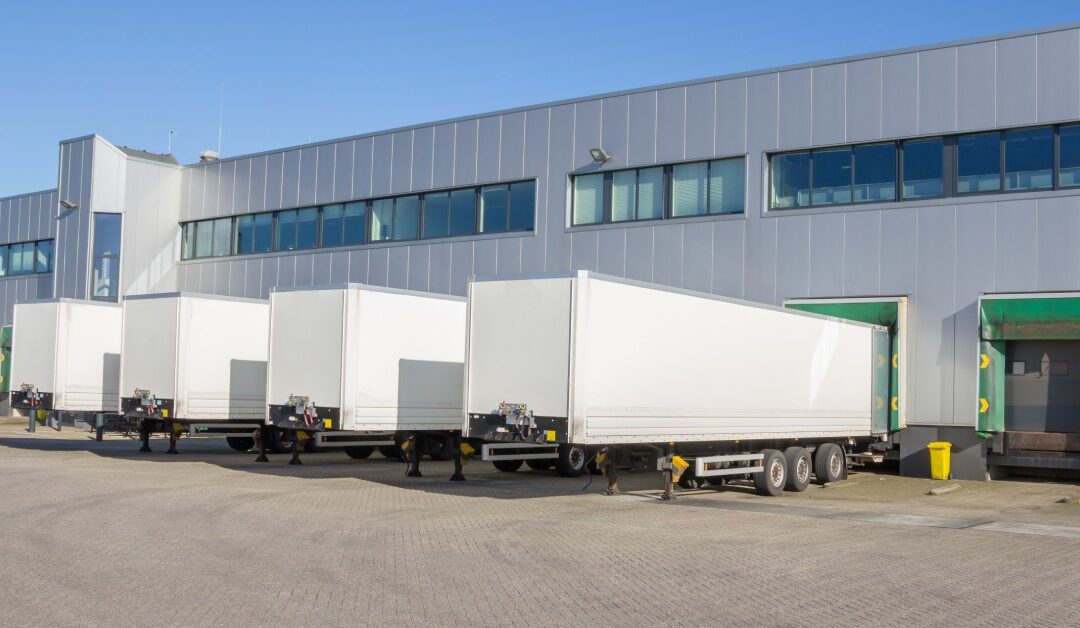 A large warehouse with multiple storage trailers parked into individual garages. There is one open garage next to them.