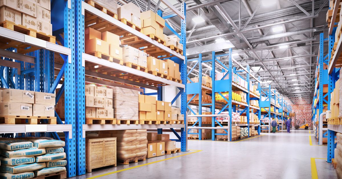 A wide shot of the interior of a warehouse, with blue rows of pallet racking holding cardboard boxes of inventory.