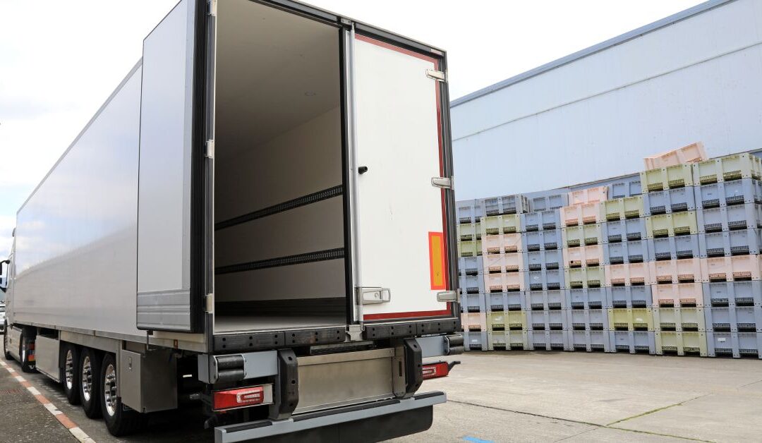 The back of a white trailer truck with the left back door swung open to reveal an empty compartment inside.